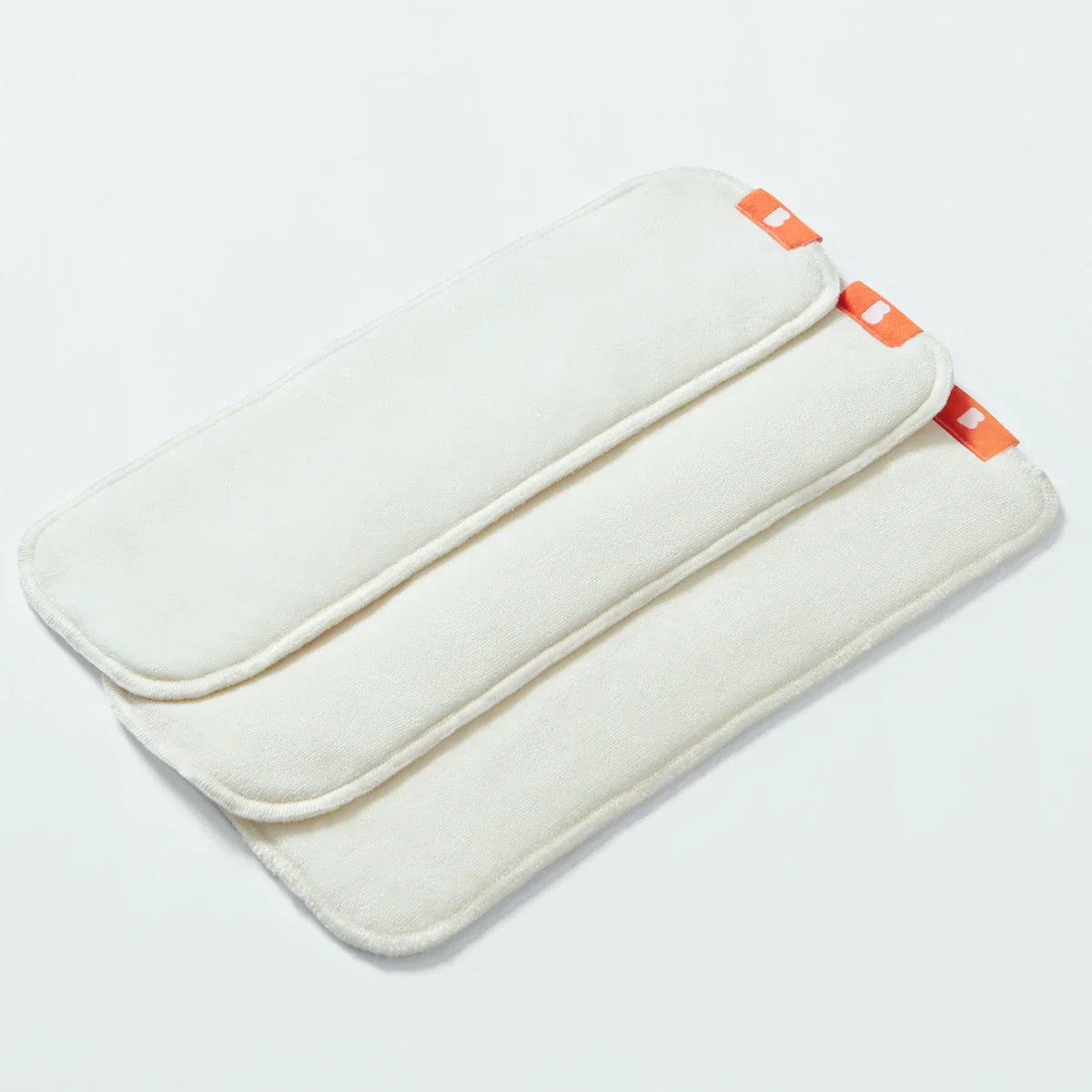 White nappy liner booster pad with orange accents on a light gray background