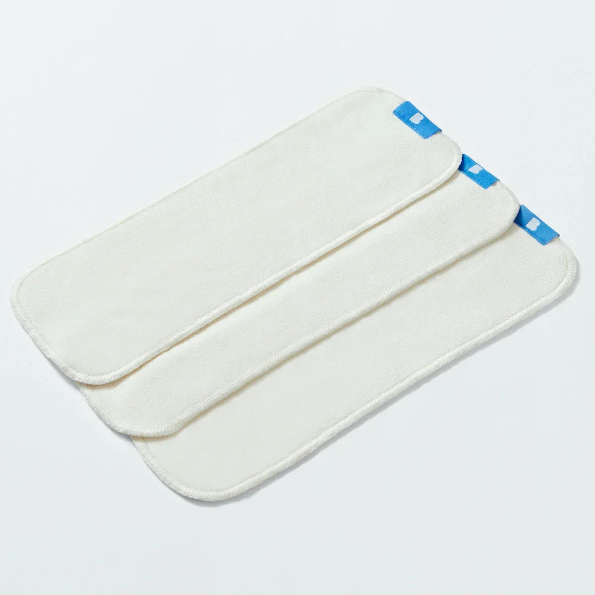White nappy boosters with blue accents on a light gray background