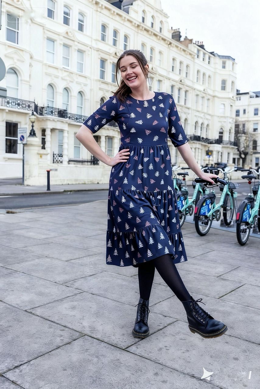 Woman in a blue dress with a pattern standing on a city street.