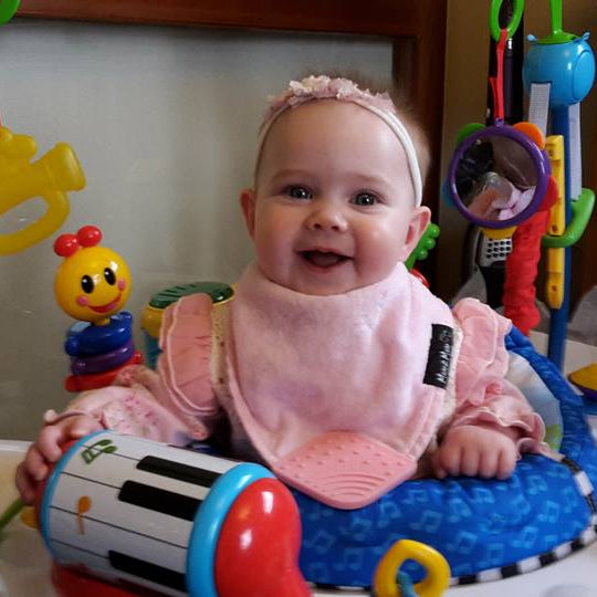 Baby in a colorful baby bouncer with various toys