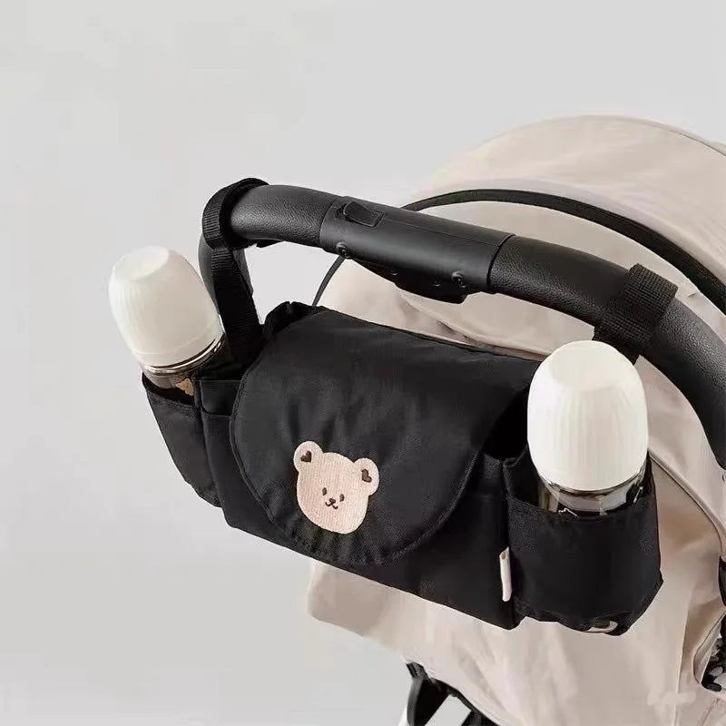 Black stroller organizer with bear emblem holding two bottles on a light gray background