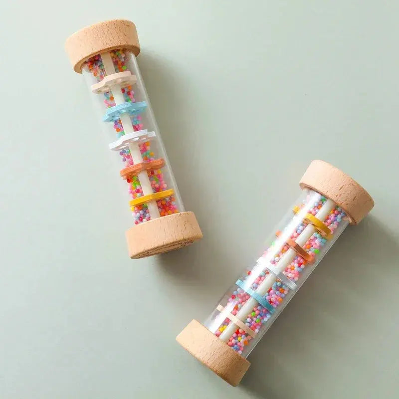 Two glass tubes with colorful beads and wooden caps on a light gray background