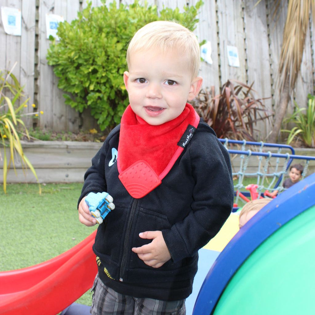 Child wearing a red bandana and black jacket in an outdoor playground setting