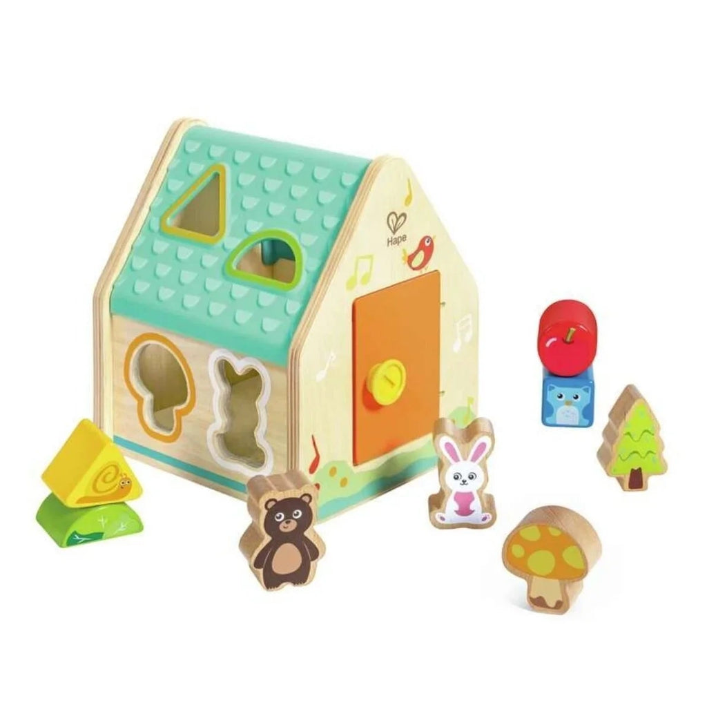 Wooden toy house with various shaped pieces on a white background