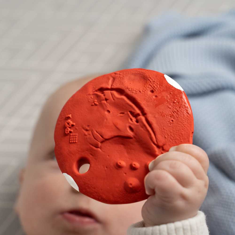 Red textured object held by a child's hand with a soft focus background