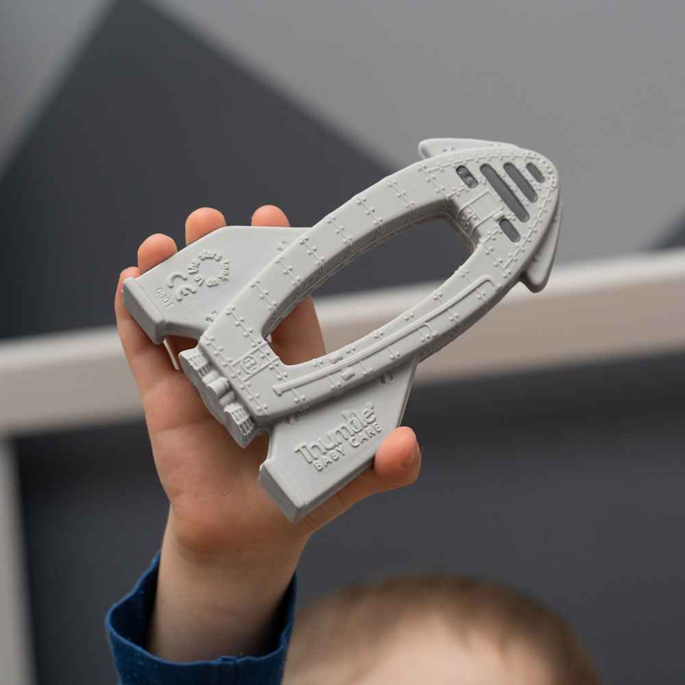 Child holding a gray plastic tool with 'Huttlle' branding against a neutral background